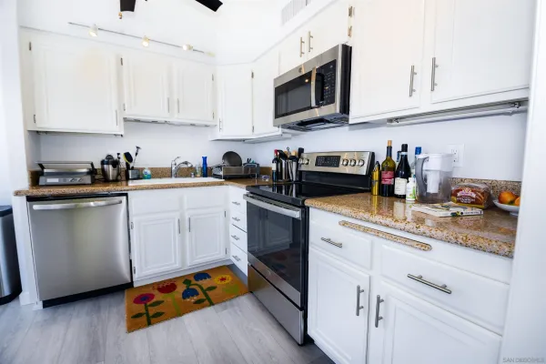 a kitchen with stainless steel appliances granite countertop white cabinets a sink and dishwasher