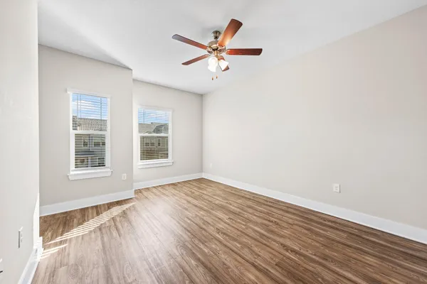 an empty room with wooden floor and windows