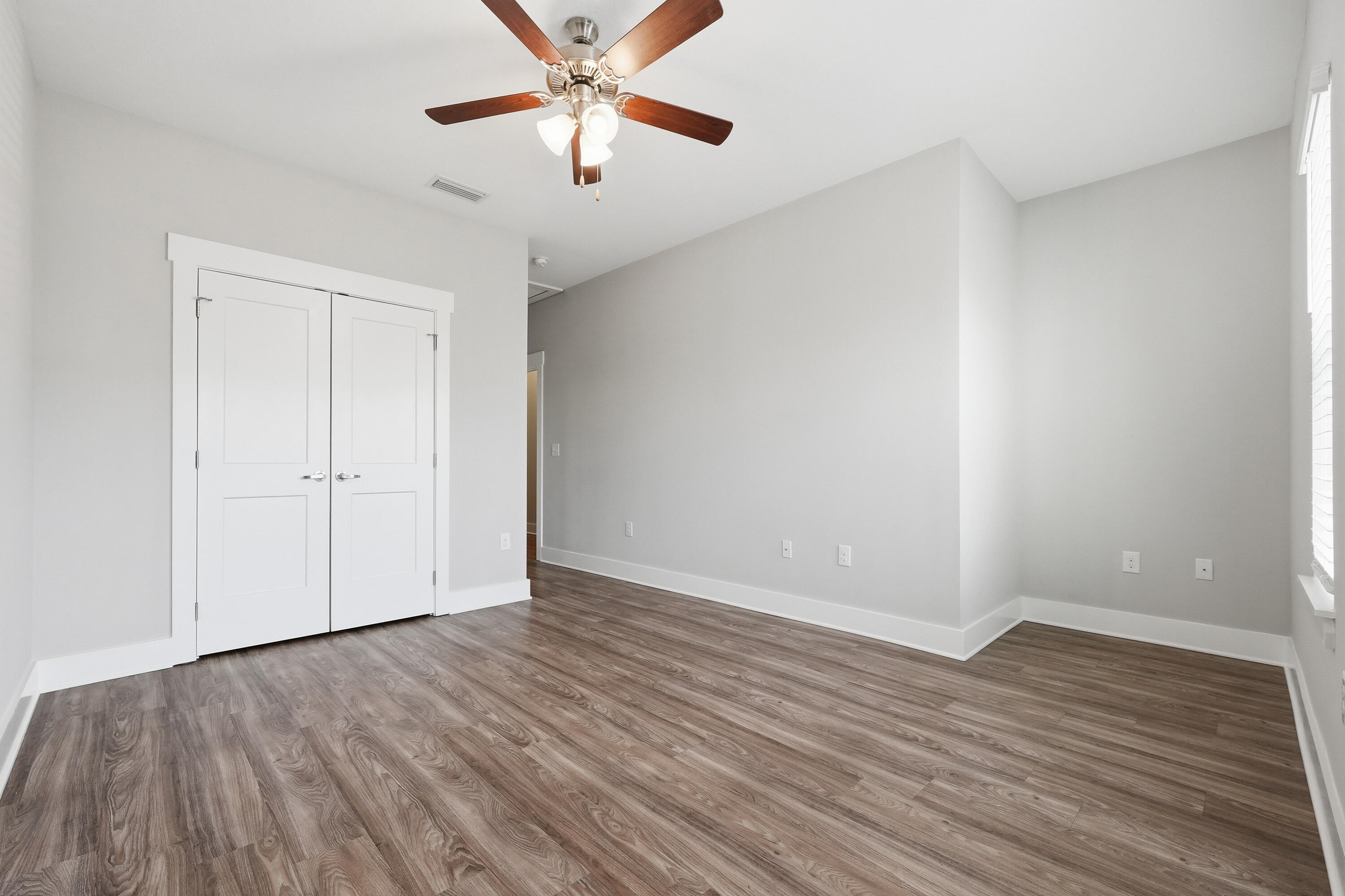 246 North Sand Palm Road Freeport, FL 32439 - Photo 24 of 42 an empty room with wooden floor chandelier fan and windows