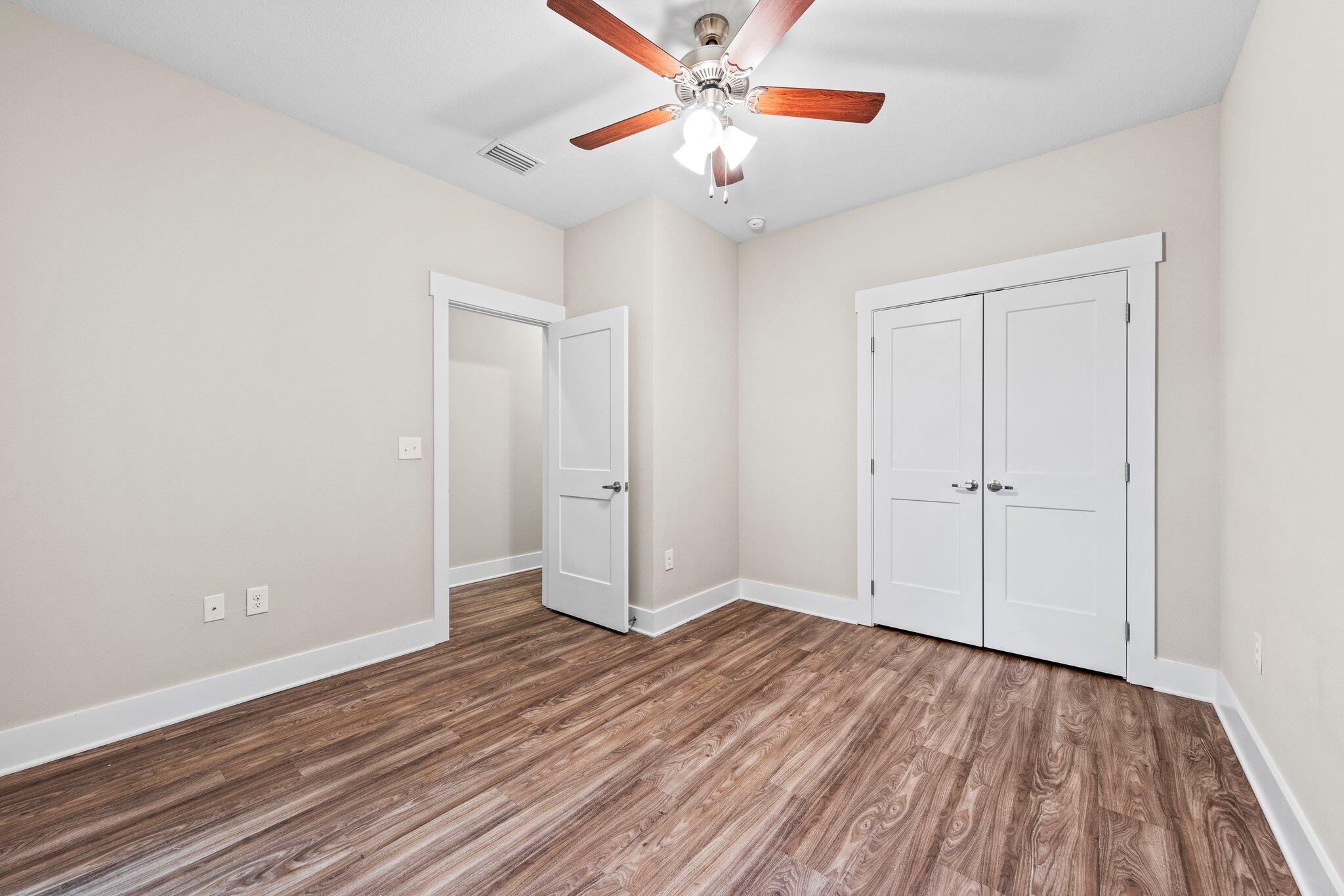 246 North Sand Palm Road Freeport, FL 32439 - Photo 25 of 36 an empty room with wooden floor chandelier fan and windows