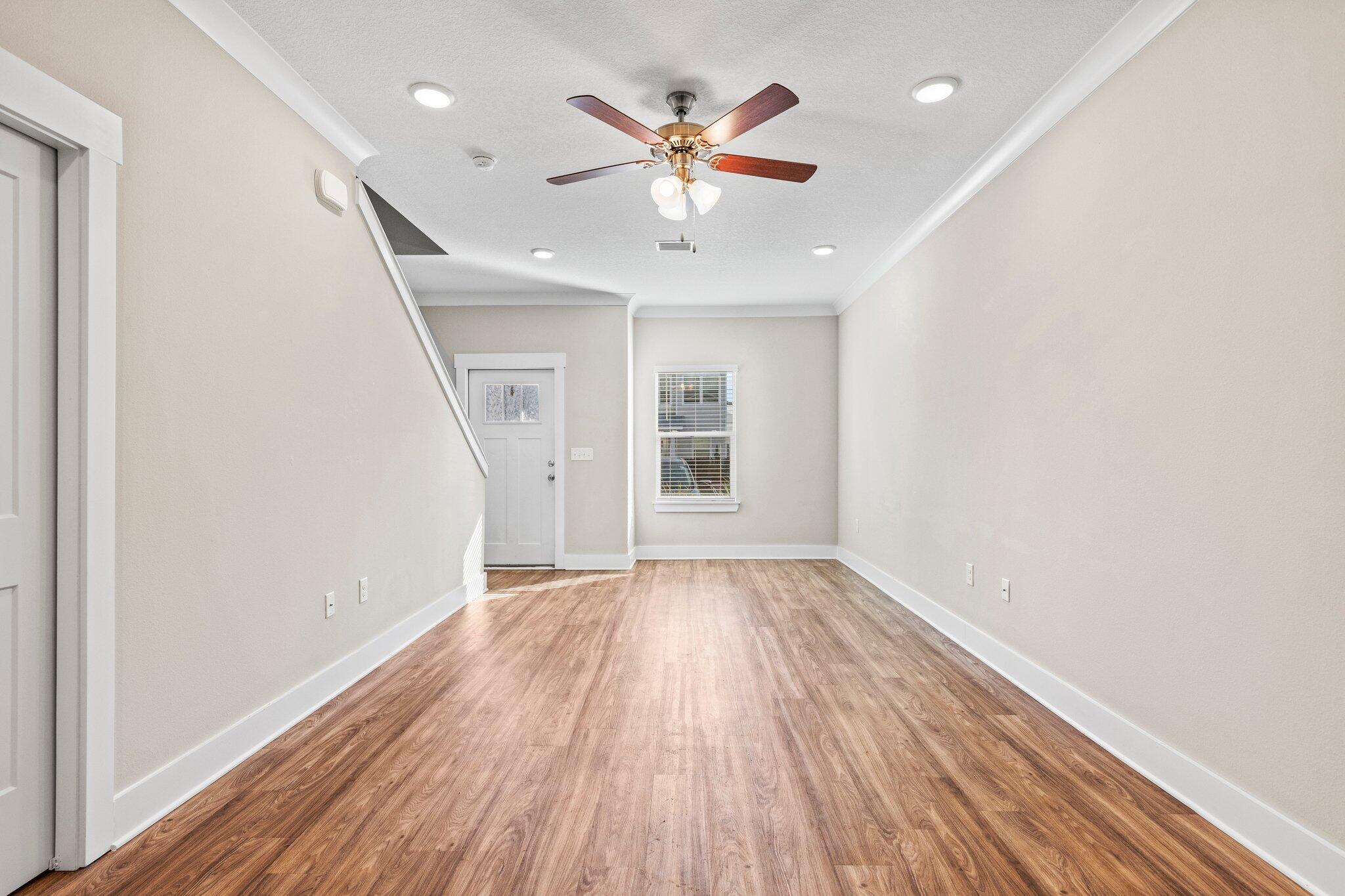 246 North Sand Palm Road Freeport, FL 32439 - Photo 6 of 36 an empty room with wooden floor ceiling fan and windows