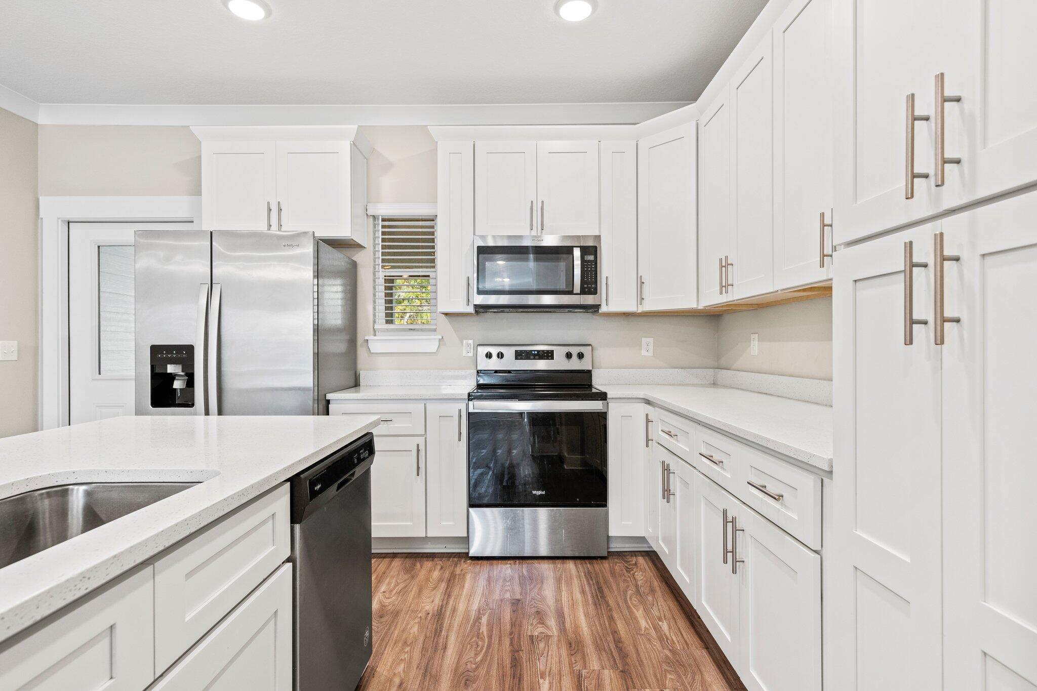 246 North Sand Palm Road Freeport, FL 32439 - Photo 10 of 36 a kitchen with cabinets stainless steel appliances a sink and wooden floor