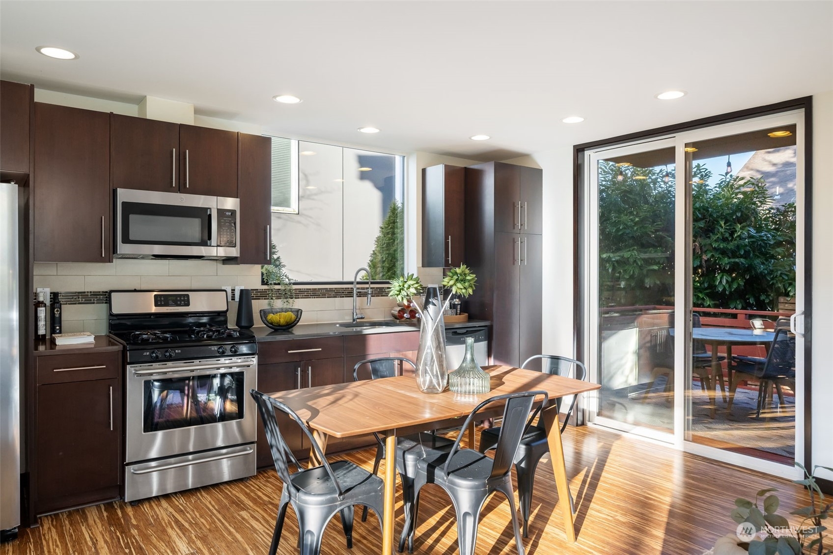 830 Northwest 53rd Street, Unit B Seattle, WA 98107 - Photo 11 of 28 a kitchen with stainless steel appliances granite countertop a stove top oven a sink dishwasher a dining table and chairs with wooden floor