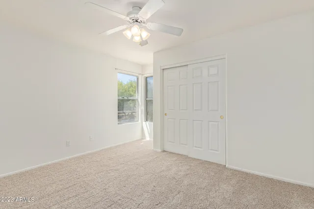 an empty room with a ceiling fan and a window