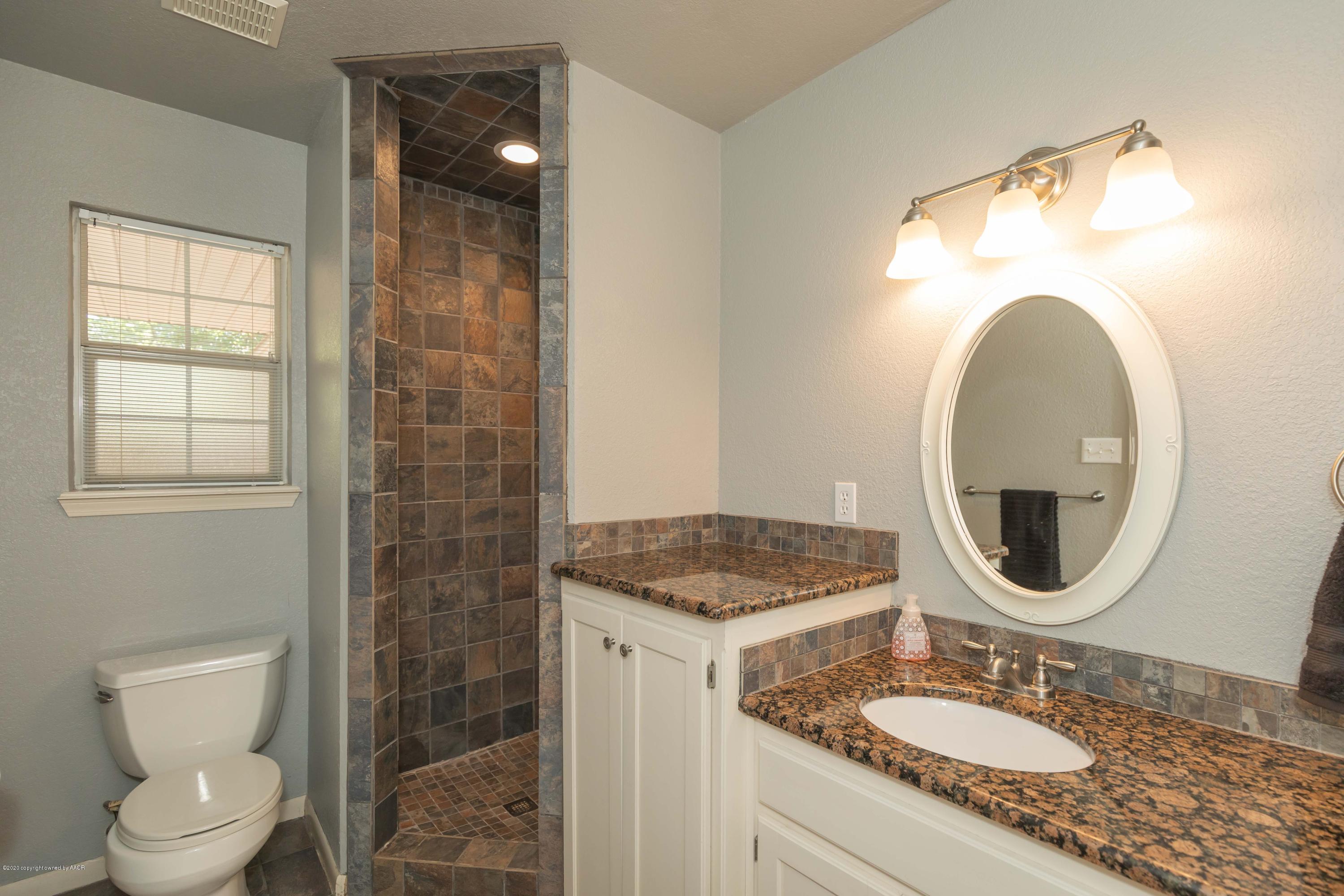 6710 Jameson Road Amarillo, TX 79106 - Photo 32 of 40 a bathroom with a granite countertop sink a mirror and a toilet