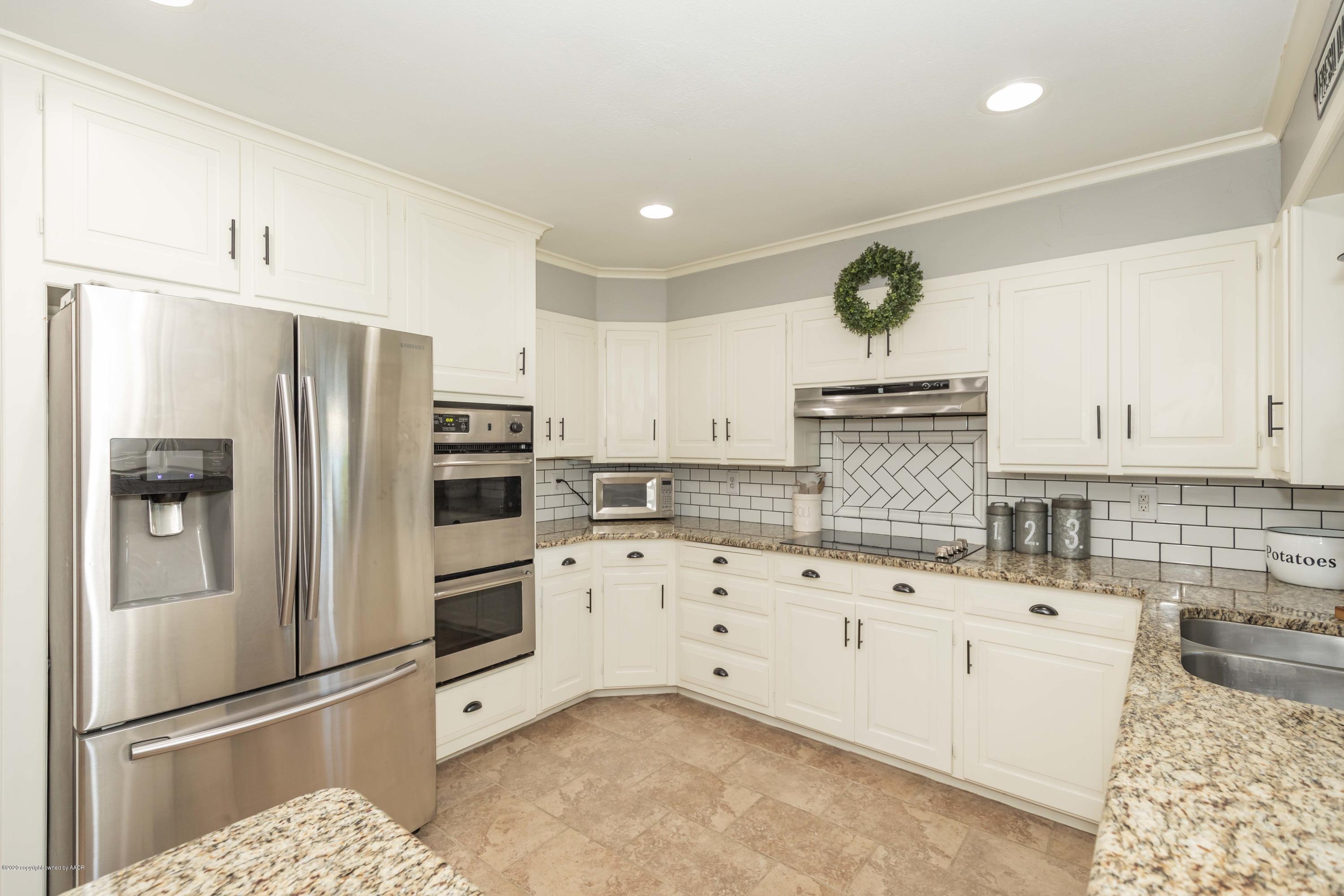 6710 Jameson Road Amarillo, TX 79106 - Photo 6 of 40 a kitchen with granite countertop a refrigerator oven a sink and white cabinets