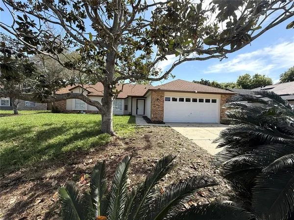 a front view of a house with garden and trees