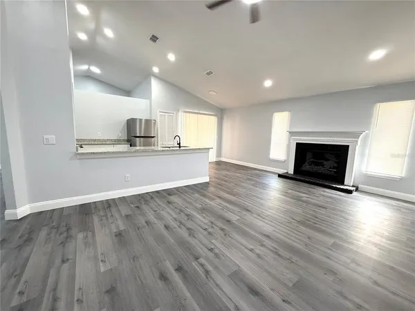 an empty room with wooden floor fireplace and window