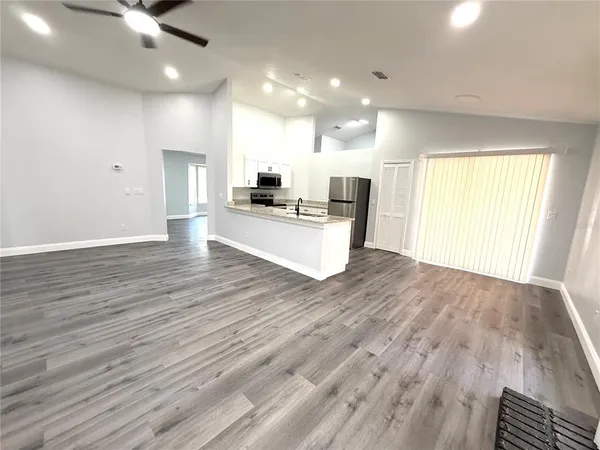 a view of a kitchen with kitchen island a counter top space a sink wooden floor and a living room view