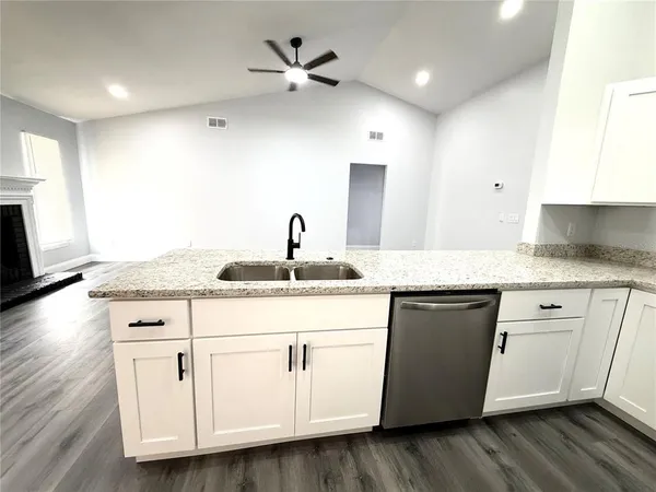 a kitchen with granite countertop white cabinets white appliances with wooden floor and a sink