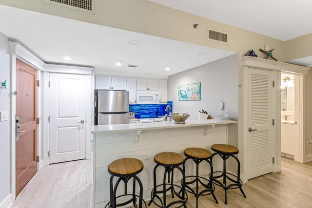 a kitchen with stainless steel appliances a dining table chairs refrigerator and wooden cabinets