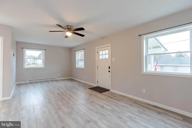 a view of an empty room with a window and wooden floor