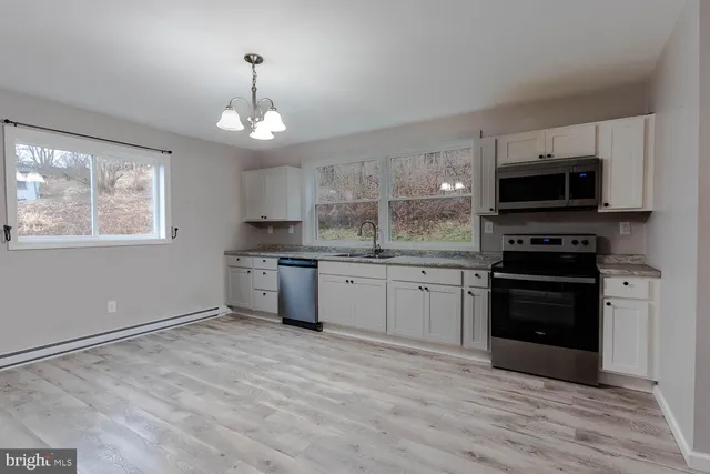 a kitchen with granite countertop a stove a sink and a microwave