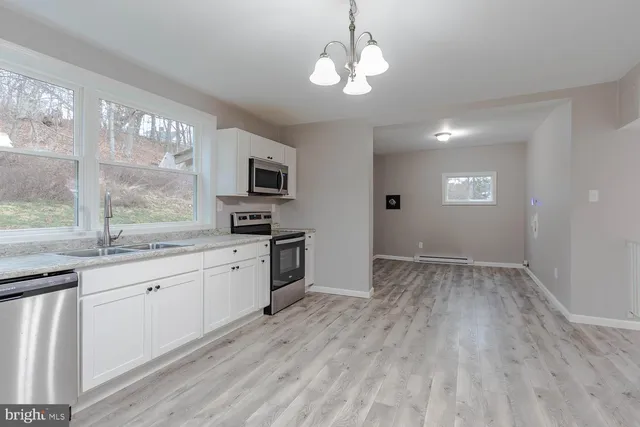 a open kitchen with granite countertop a stove top oven a sink dishwasher a dining table and chairs with wooden floor