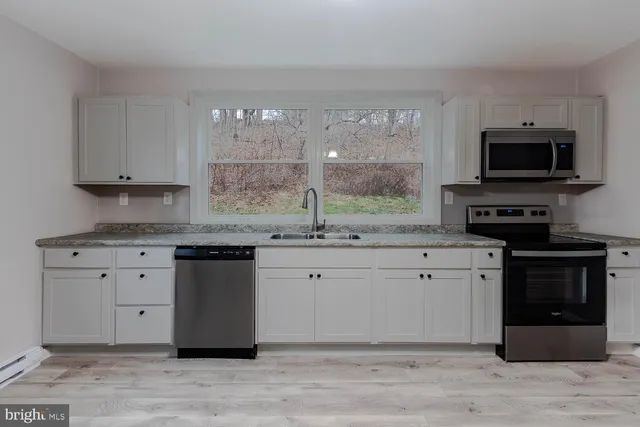 a kitchen with stainless steel appliances granite countertop a stove a sink and a microwave