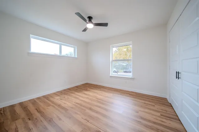 a view of empty room with wooden floor and fan