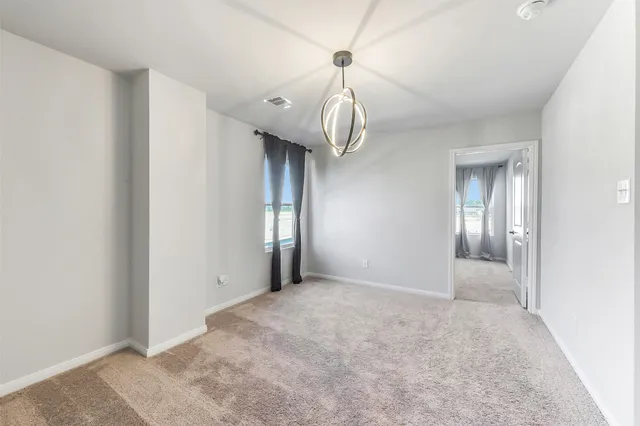 a view of an empty room with a chandelier fan