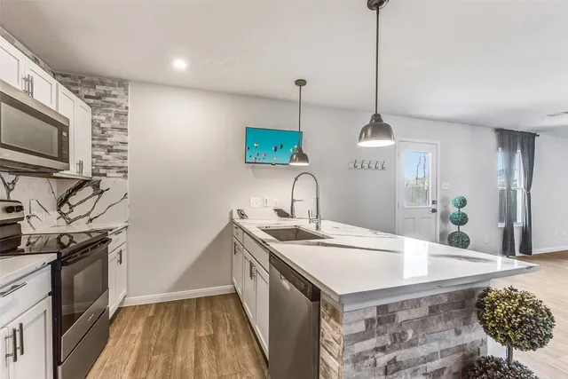 a kitchen with stainless steel appliances granite countertop a sink a stove and a wooden floor