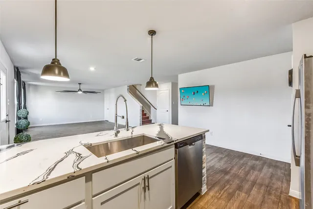 a kitchen that has a sink a microwave oven a stove and white cabinets with wooden floor