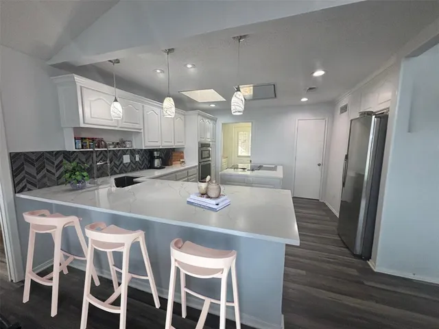 a kitchen with stainless steel appliances kitchen island granite countertop a kitchen island and chairs in it