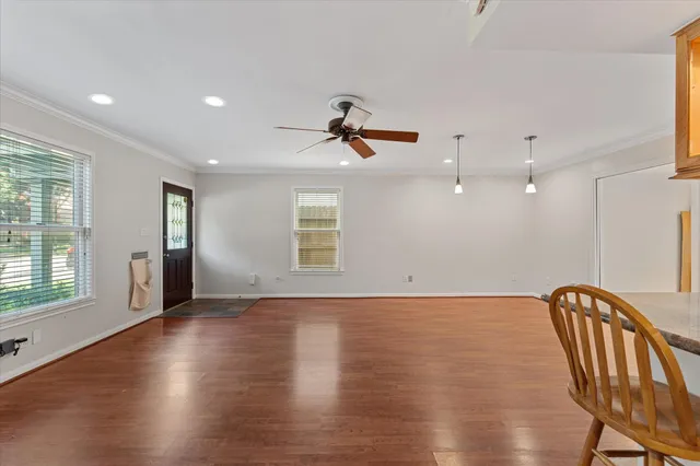 a view of an empty room with a window and wooden floor