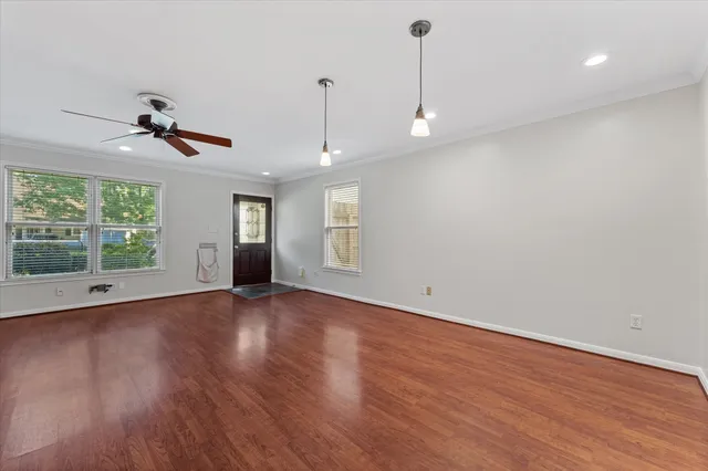a view of an empty room with wooden floor and a window