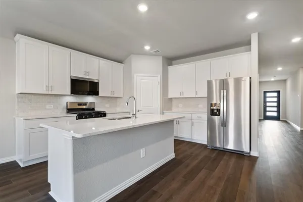 a kitchen with a refrigerator a stove top oven a sink and cabinets