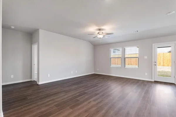 a view of an empty room with a window and wooden floor