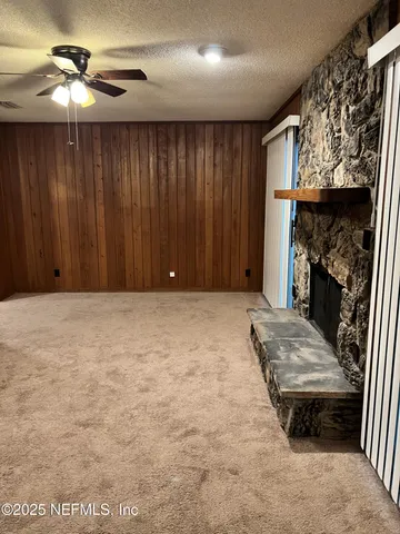 an empty room with ceiling fan and a fireplace