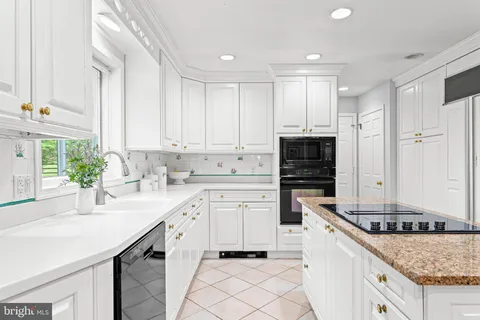 a kitchen with stainless steel appliances granite countertop white cabinets a sink and a window