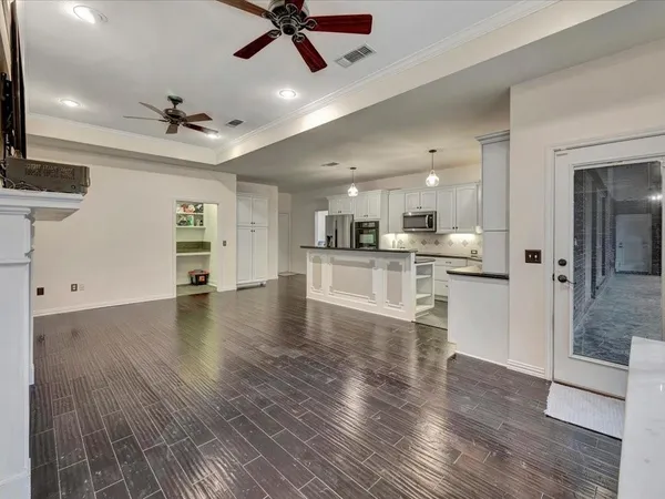 a view of a kitchen with a refrigerator a ceiling fan and wooden floor