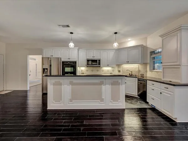 a kitchen with stainless steel appliances granite countertop a stove a sink and white cabinets