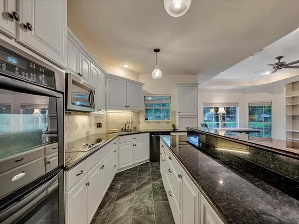 a large kitchen with stainless steel appliances a large counter top a stove and a sink