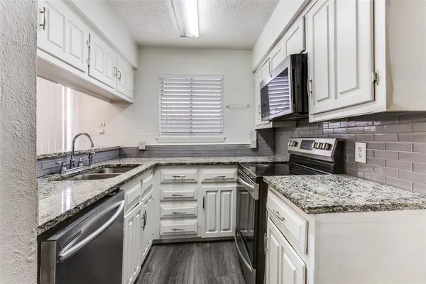a kitchen with granite countertop a sink stove and cabinets
