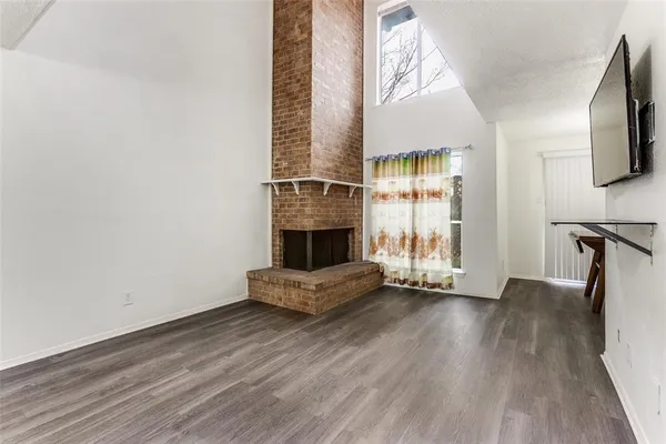 an empty room with wooden floor fireplace and windows