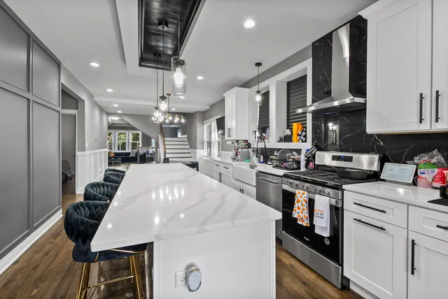 a kitchen with stainless steel appliances a table chairs in it and wooden floors