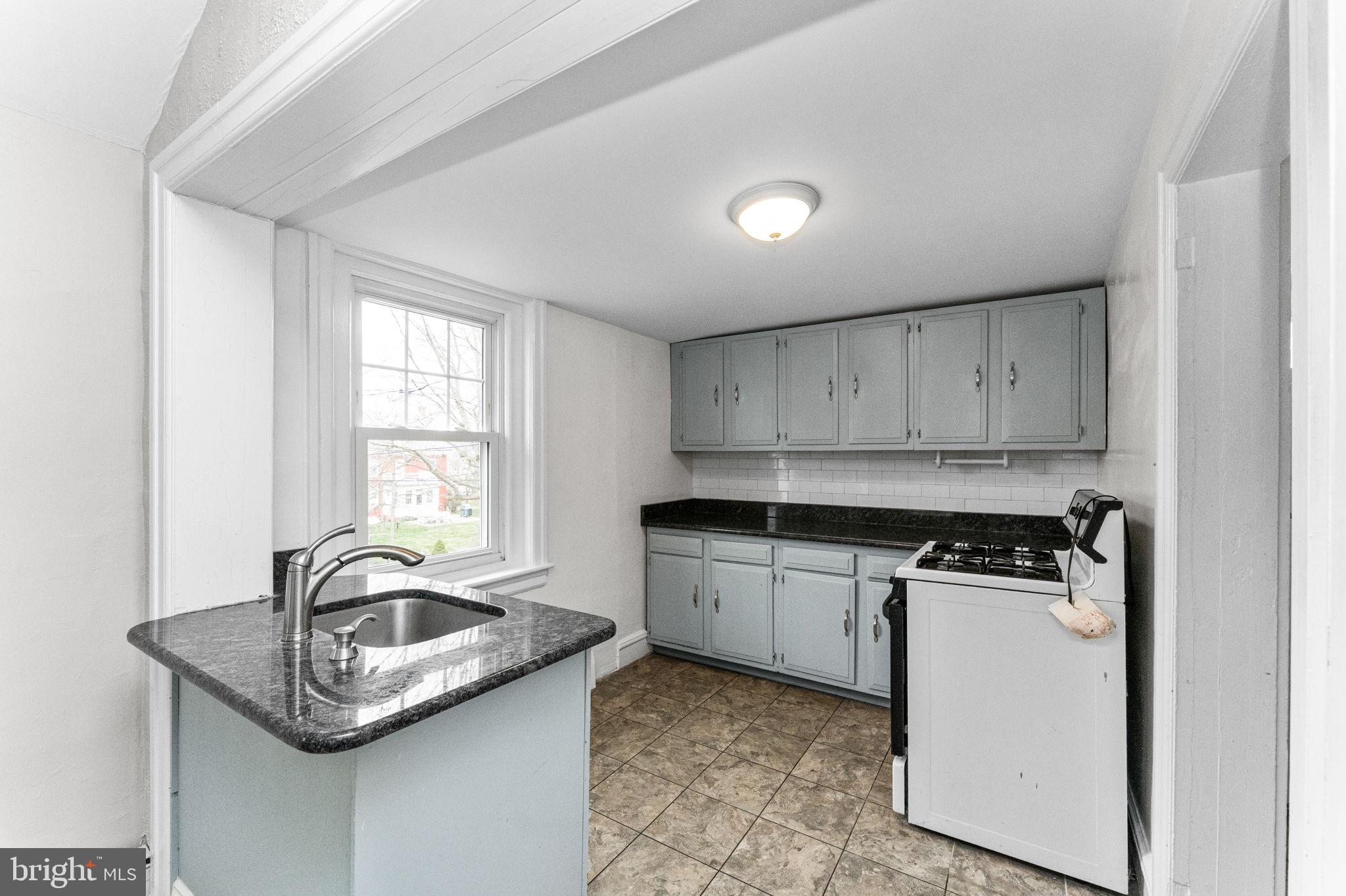 255 Noble Street, Unit B Souderton, PA 18964 - Photo 4 of 15 a kitchen with granite countertop a sink a stove and cabinets