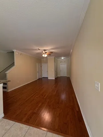 a view of a room with wooden floor and a ceiling fan