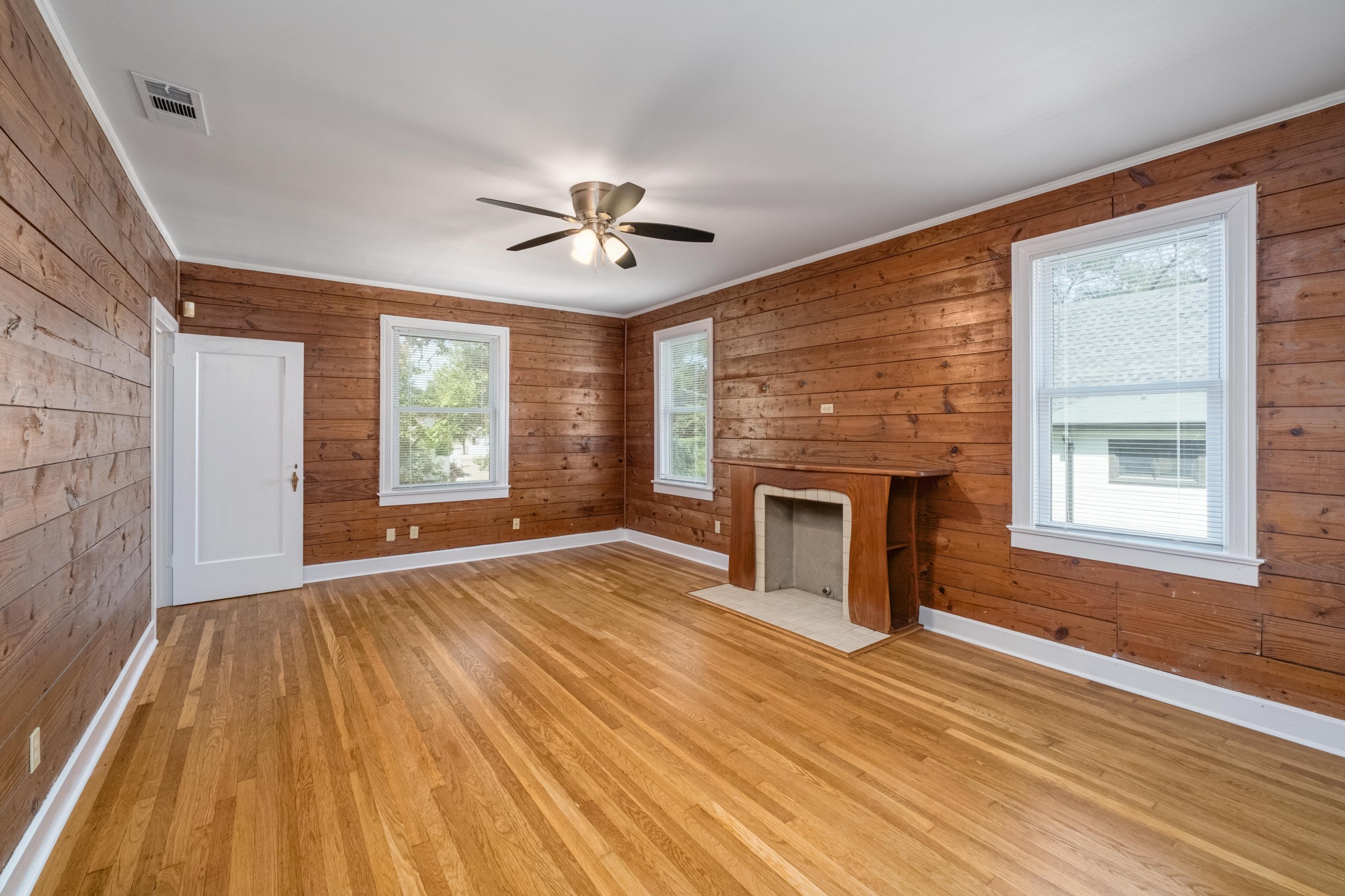 2012 Enfield Road, Unit B Austin, TX 78703 - Photo 3 of 20 A well-lit living area featuring rich wood paneling, gleaming hardwood floors, and a charming fireplace.