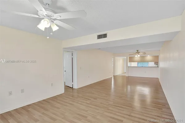 an empty room with wooden floor chandelier fan and windows