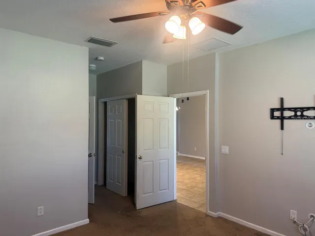 a view of a hallway with closet and a chandelier fan