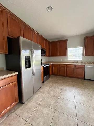 a kitchen with granite countertop a refrigerator and a stove top oven