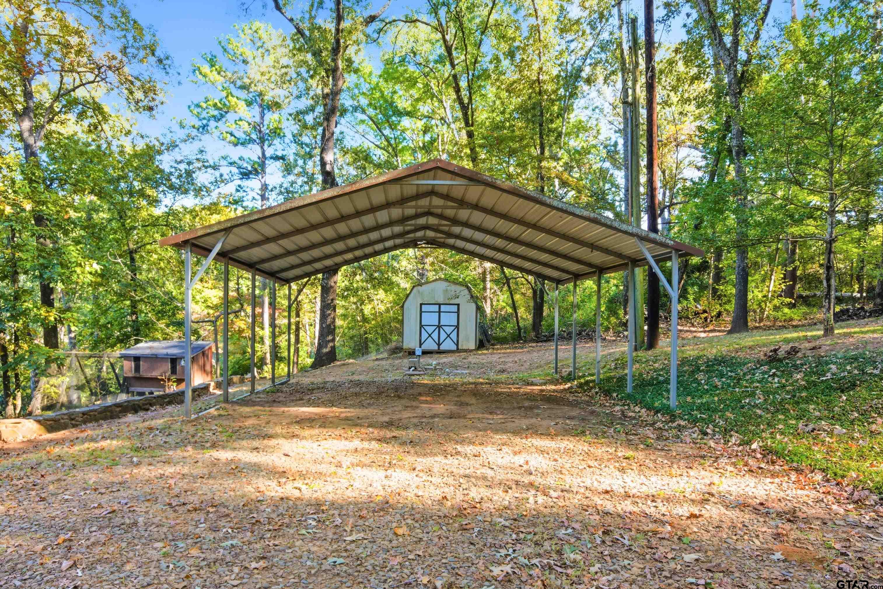14525 Lake Road West Tyler, TX 75709 - Photo 8 of 30 a backyard of a house with large trees and table and chairs