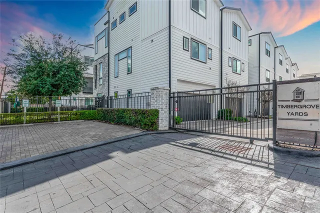 a view of a white house next to a yard with big trees