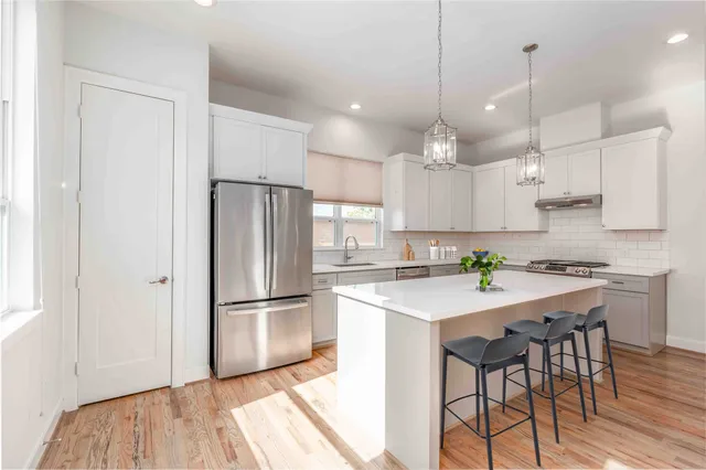 a kitchen with granite countertop a refrigerator a sink and white cabinets