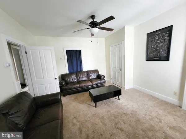 a living room with furniture rug and a ceiling fan
