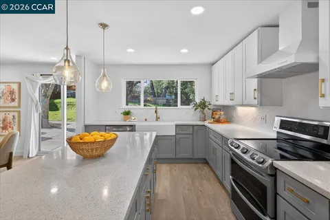 a kitchen with stainless steel appliances granite countertop a sink a stove and a wooden floors