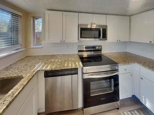 a kitchen with granite countertop a stove and a sink