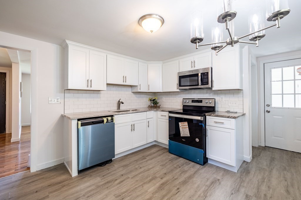 10 Sibley Street Three Rivers, MA 01080 - Photo 9 of 18 a kitchen with granite countertop a refrigerator a stove top oven a sink and dishwasher with wooden floor