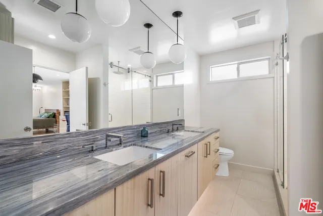 a bathroom with a granite countertop sink a toilet a mirror and vanity